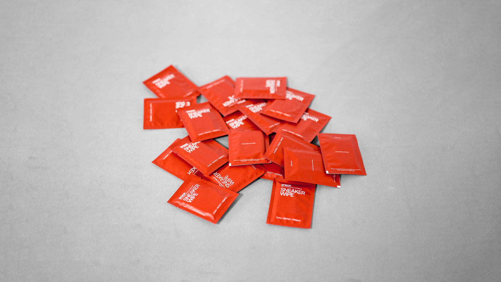 SPBOX sneaker wipe sachets scattered on a grey surface
