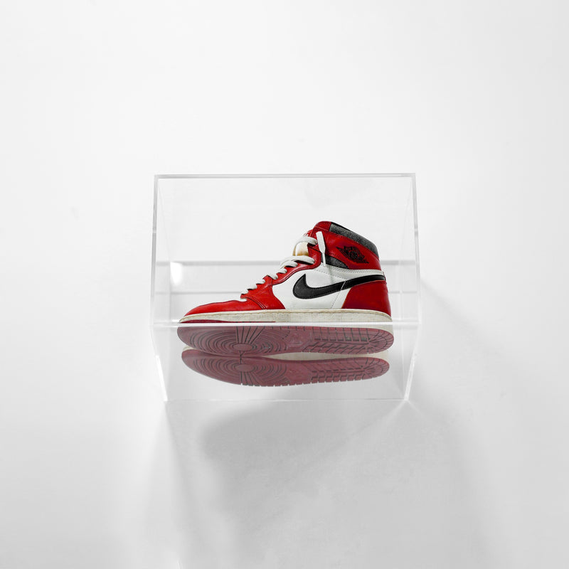 Red and white sneaker sealed inside a clear SPBOX case on a white background