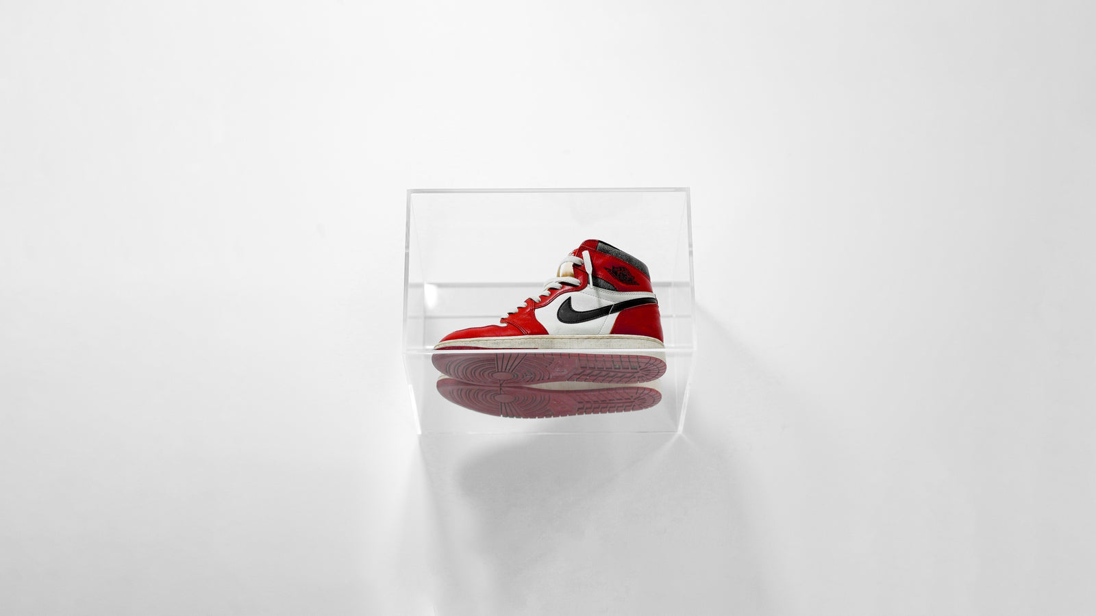 Red and white sneaker sealed inside a clear SPBOX case on a white background